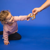 A little girl has a fruit shot 1SHOT in her hand and toasts with another fruit shot 1SHOT held by another person.