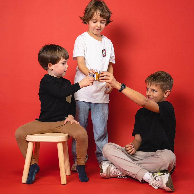 Trois garçons trinquent chacun avec un shot de fruits 1SHOT dans un flacon de 30 ml.