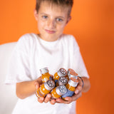 A boy holds eight Frucht Shot 1SHOTs in both hands and holds them up to the camera.