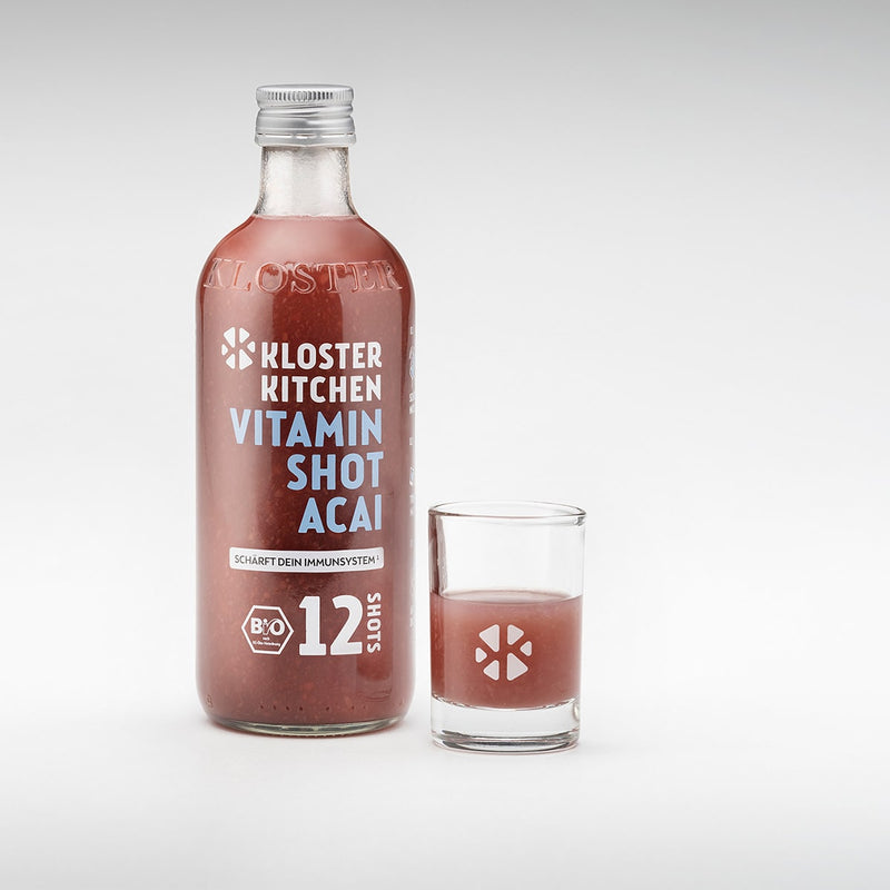 Le shot vitaminé au goût d'açai dans une bouteille de 360 ml avec un verre à shot rempli à côté.