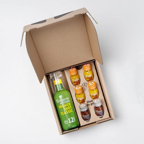 Close-up of the contents of the Hot Shot Box: 60 ml bottle of Ginger Shot Classic, next to it small 30 ml bottles with 4x Ginger Shot Turmeric and 2x Vitamin Shot Acai