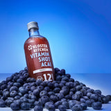 The contents of a Ginger Shot Mix Box Summer from Kloster Kitchen: Vitamin Shot Acai 360 ml bottle in a bunch of acai berries.