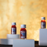 Three vitamin shots of acai on small pedestals.