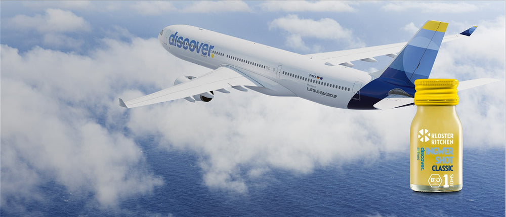 L'avion de Discover Airlines dans les airs entre les nuages, devant le shot de Kloster Kitchen et Discover Airlines