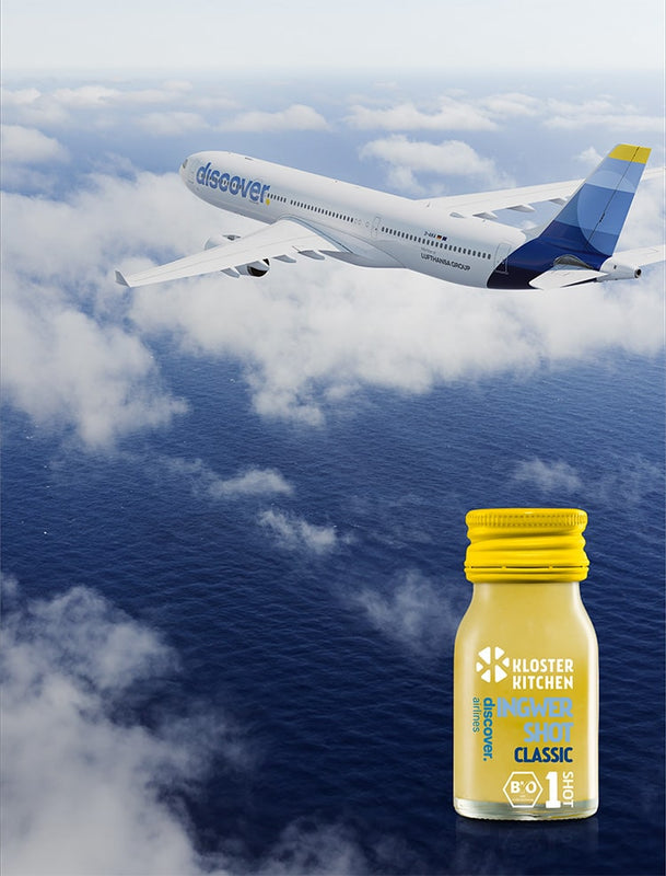L'avion de Discover Airlines dans les airs entre les nuages, devant le shot de Kloster Kitchen et Discover Airlines