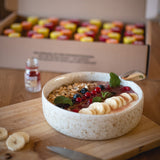 Un bol de aspecto saludable, al fondo también se ve un chupito de jengibre vacío y el envase abierto de la cura de chupito de jengibre.