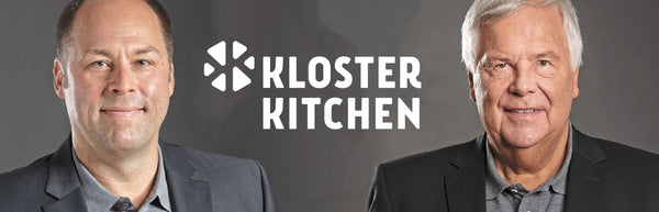 Mario Fürst and Hans Rudolf Wöhrl in suits in front of a grey Kloster Kitchen logo