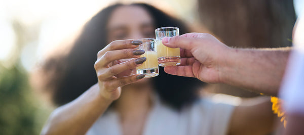 Recruit friends: two people toast each other with a shot glass