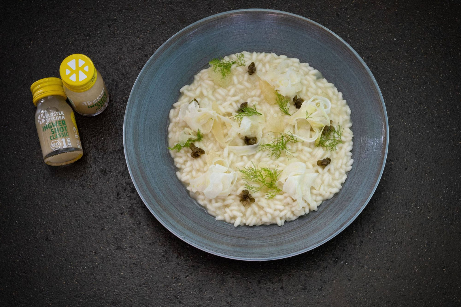Fennel risotto served in a blue plate with two Kloster Kitchen Ginger Shots Classic next to it