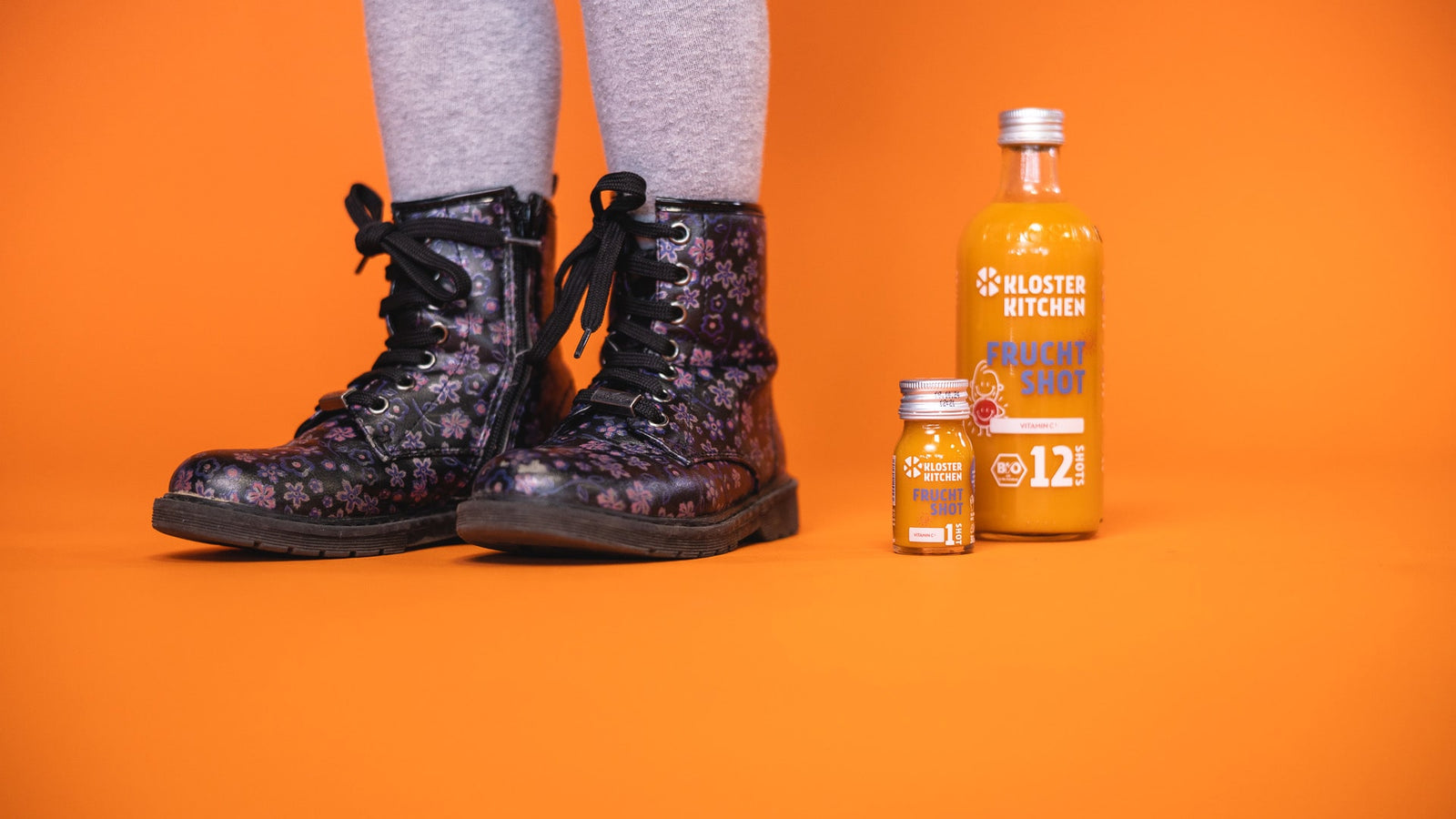 New product from Kloster Kitchen - the fruit shot in the large 360 ml bottle and the 30 ml bottle - next to a pair of children's feet.