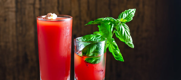 Two glasses with the drink "Fiery Basil Rush" decorated with basil leaves.