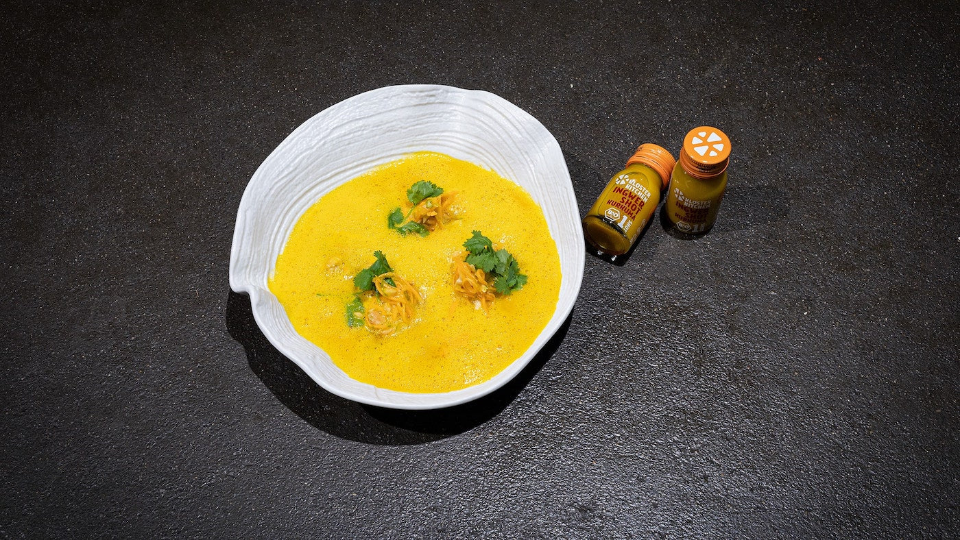 Die angerichtete Süßkartoffel Kurkuma Ingwer Suppe, daneben 2 Ingwer Shot Kurkuma
