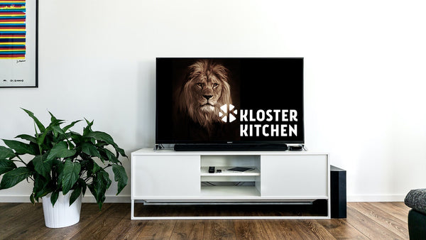 Un televisor con un león encima, como en el programa de televisión "Höhle der Löwen", con el logotipo de Kloster Kitchen al lado. 