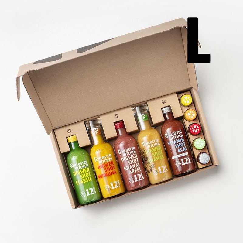 The open ginger shot tasting set L from Kloster Kitchen. In the open box are 5 times 360 ml bottles: Ginger Shot Classic, Ginger Shot Turmeric, Ginger Shot Pomegranate, Ginger Shot Pineapple and Ginger Shot Cranberry Horseradish. In addition, there is also a small 30 ml bottle of each flavor.