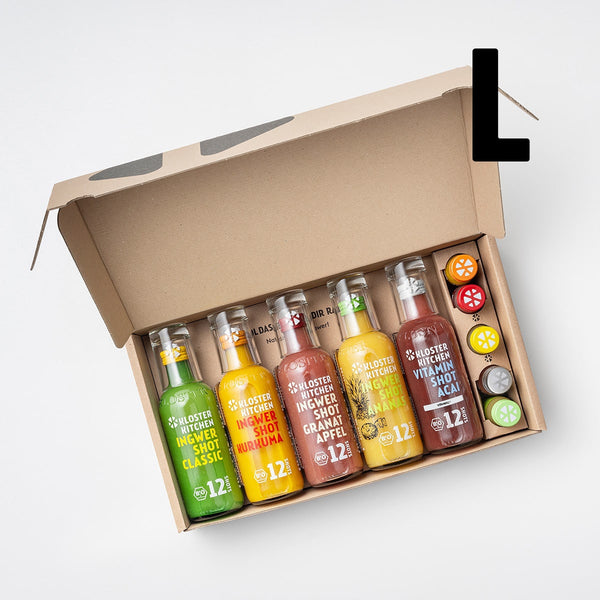 The open ginger shot tasting set L from Kloster Kitchen. In the open box are 5 times 360 ml bottles: Ginger Shot Classic, Ginger Shot Turmeric, Ginger Shot Pomegranate, Ginger Shot Pineapple and Ginger Shot Cranberry Horseradish. In addition, there is also a small 30 ml bottle of each flavor.
