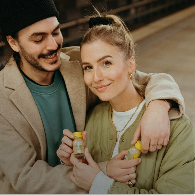 Ein Mann umarmt eine Frau, beide haben jeweils einen Ingwer Shot Classic in der Hand