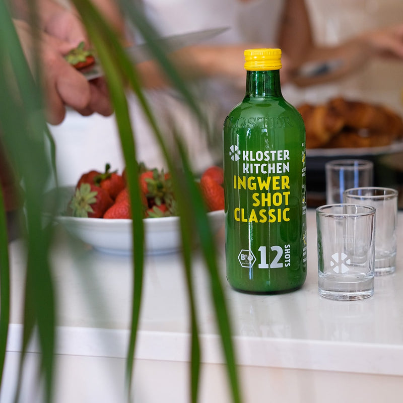 Bicchieri per ginger shot: una bottiglia di ginger shot da 360 ml accanto a bicchieri vuoti per ginger shot, pronti per essere riempiti.