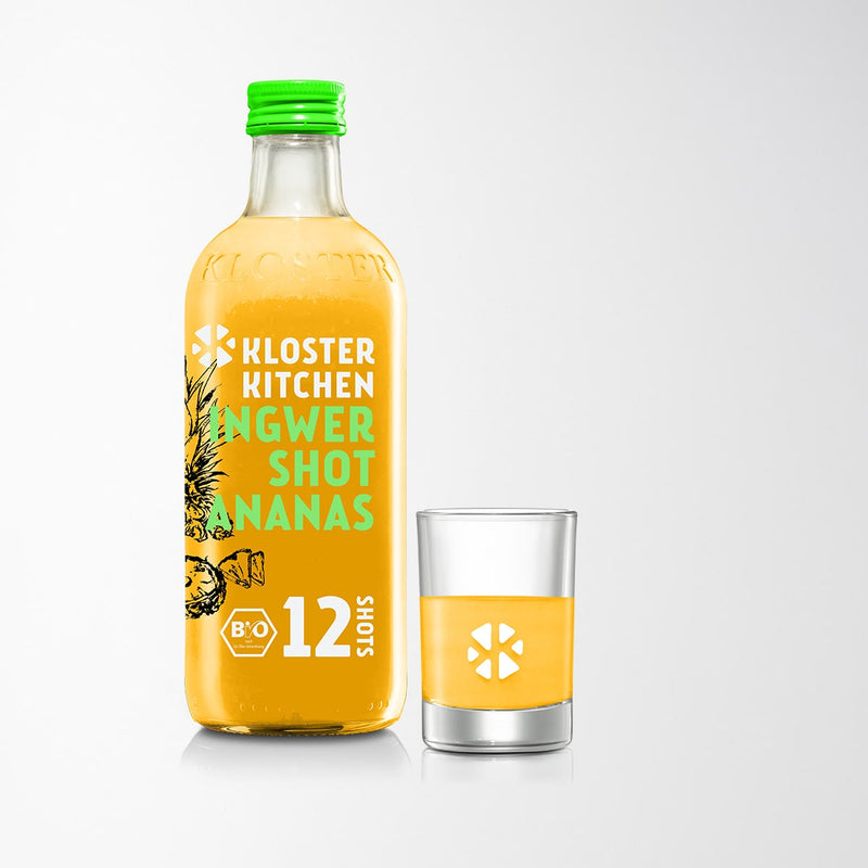 Der Ingwer Shot in der Geschmacksrichtung Ananas in der 360 ml Flasche mit einem gefüllten Shot Glas daneben