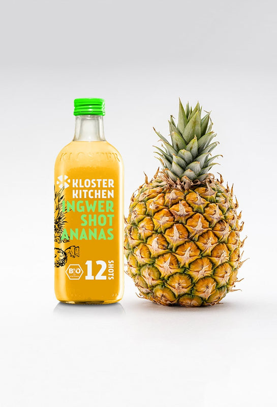 Un Ginger Shot Pineapple 12SHOTS (bottiglia da 360 ml con 12 porzioni) accanto a un ananas