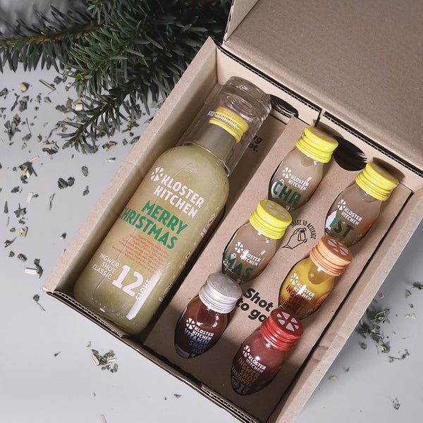 Ingwer Shot Geschenkbox Weihnachten: Box liegt offen da, damit man den Inhalt sieht: 1x Ingwer Shot Classic 360 ml im XMAS Design, 3x Ingwer Shot Classic 30 ml im XMAS Design, 1x Ingwer Shot Kurkuma 30 ml, 1x Ingwer Shot Granatapfel 30 ml, 1x Ingwer Shot Acai 30 ml 