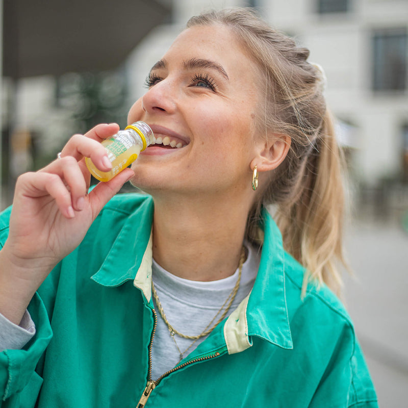 Inhalt des Ingwer Shot Probierset L: Frau führt gerade einen Ingwer Shot Classic im 30 ml Fläschchen an die Lippen.