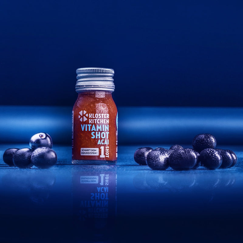 Ein Vitamin Shot Acai 1SHOT neben Acai Beeren.