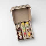 Geöffnete Kloster Kitchen Geschenkbox mit einer Ingwer-Shot-Flasche Beere-Zimt und sechs bunten Mini-Shots in Gelb, Grün, Rot und Silber