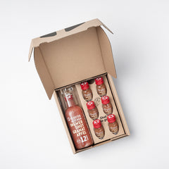 Die Ingwer Shot Geschenkbox Muttertag offen. Darin sind 6 mal 30 ml Fläschchen Ingwer Shot Granatapfel mit Limited Edition Herzchen Design und eine 360 ml Flasche Ingwer Shot Granatapfel im Limited Edition Herzchen Design sowie ein Shot Glas.