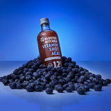 Der Vitamin Shot Acai 12SHOTS von Kloster Kitchen in einem Haufen von Acai Beeren.